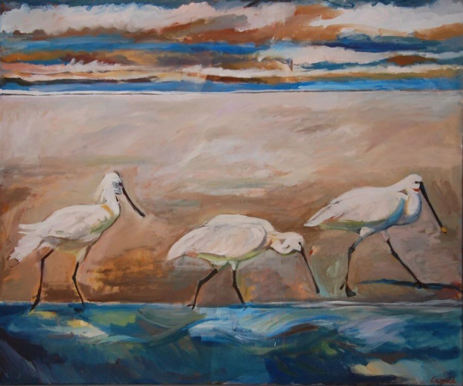Olieverfschilderij van Margreeth Leopold: drie witte lepelaars die voedsel zoeken in ondiep kustwater bij zonsondergang, met een zachtblauwe en oranje wolkenlucht